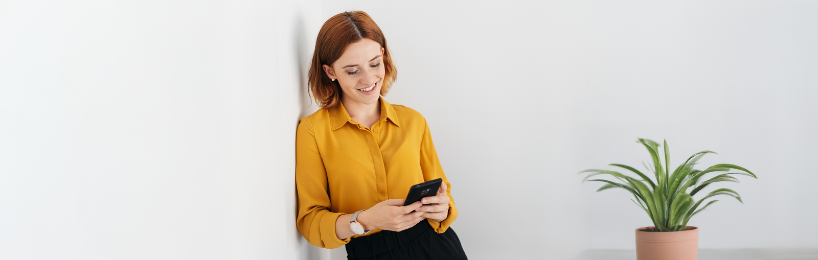 Eine freundlich lächelnde Frau mit gelber Bluse meldet sich über ihr Handy beim Vinylfreude Newsletter an