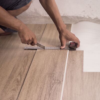 Ein Fußbodenverleger aus Berlin schneidet ganz einfach mithilfe eines Cuttermessers und eines Winkels eine Planke Vinyl an um dieses zu verlegen