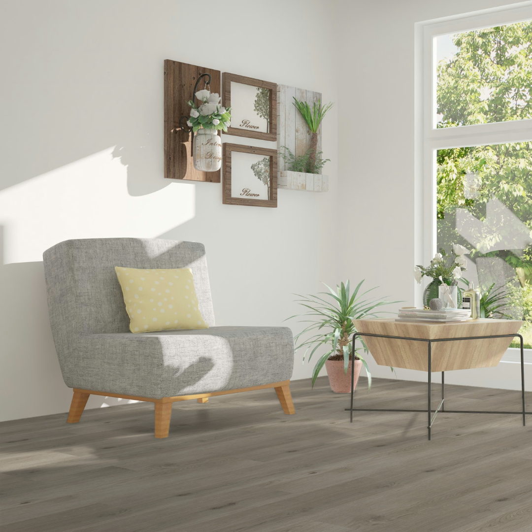 Sonnengefluteter Eckbereich mit einem grauen Sessel und einem Holztisch verlegt mit Klick Vinyl Eiche Zugspitze 
